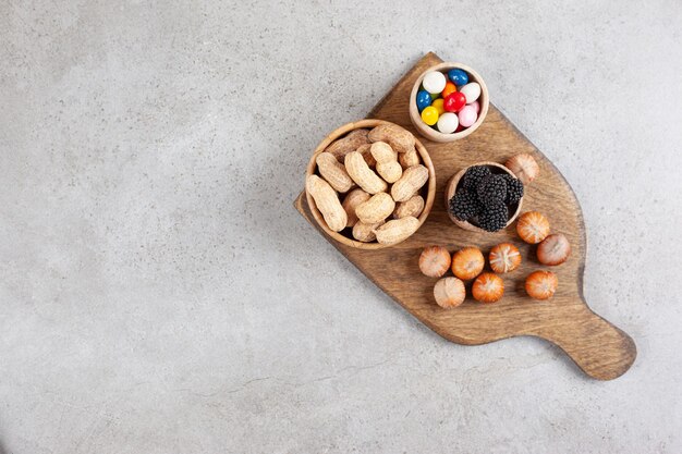 Una tabla de cortar de madera con nueces y moras.