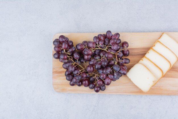 Una tabla de cortar de madera con pan de molde y uvas. Foto de alta calidad