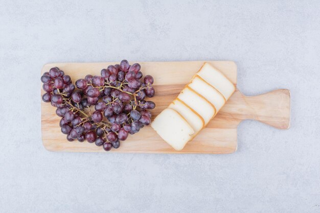 Una tabla de cortar de madera con pan de molde y uvas. Foto de alta calidad