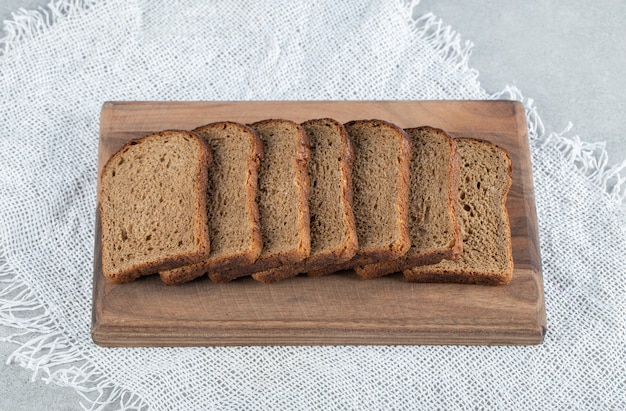 Una tabla de cortar de madera con rebanadas de pan integral.