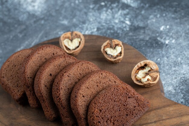 Una tabla de cortar de madera con rebanadas de pan y nueces.