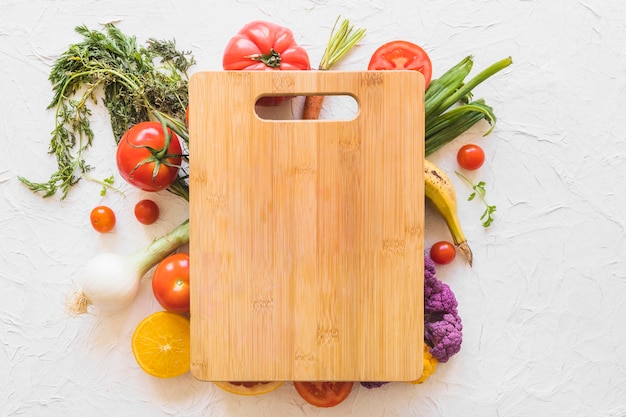 Tabla de cortar de madera sobre las verduras en el telón de fondo de textura