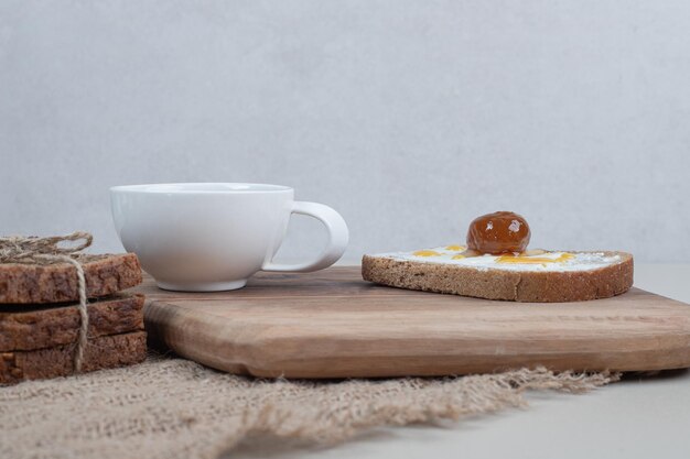 Una tabla de cortar de madera con tostadas y una taza de té en cilicio.