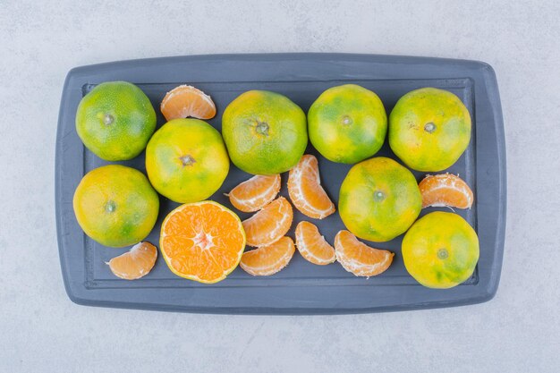 Tabla de cortar oscura completa de mandarinas amargas sobre fondo blanco. Foto de alta calidad