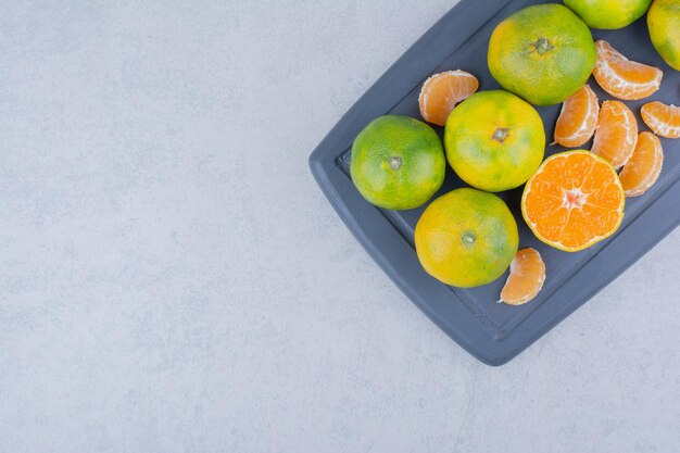 Tabla de cortar oscura completa de mandarinas amargas sobre fondo blanco. Foto de alta calidad