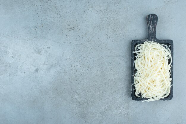 Una tabla de cortar oscura llena de queso sobre fondo azul. Foto de alta calidad