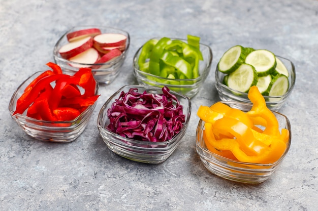 Foto gratuita tabla de cortar con rodajas de pimientos de colores sobre la superficie de la luz. rodajas de pimientos dulces en diferentes colores, ingrediente de ensalada de verduras, cocinar alimentos saludables, vista superior