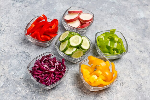 Tabla de cortar con rodajas de pimientos de colores sobre la superficie de la luz. Rodajas de pimientos dulces en diferentes colores, ingrediente de ensalada de verduras, cocinar alimentos saludables, vista superior