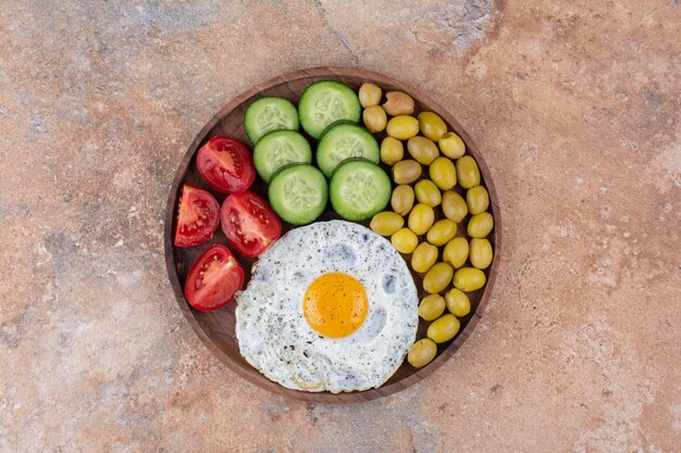 Tabla de desayuno con rebanadas de pan, verduras y huevo.