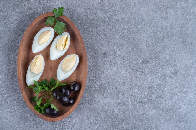 Una tabla de madera con aceitunas y huevos duros. Foto de alta calidad