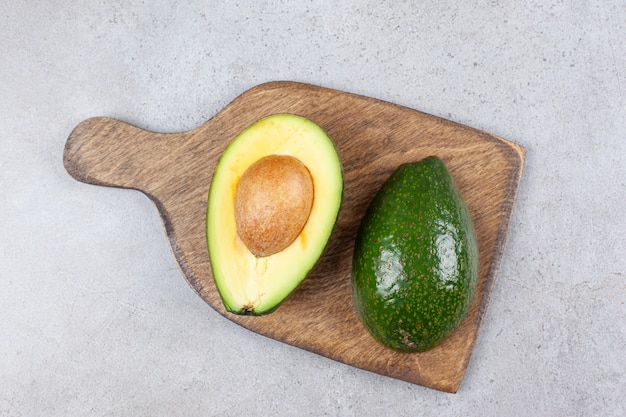 Una tabla de madera con aguacate crudo fresco en rodajas