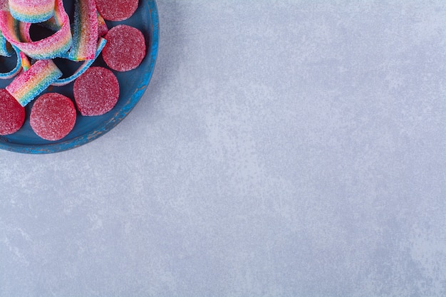 Una tabla de madera azul de dulces de gelatina roja azucarada con regaliz dulce arco iris