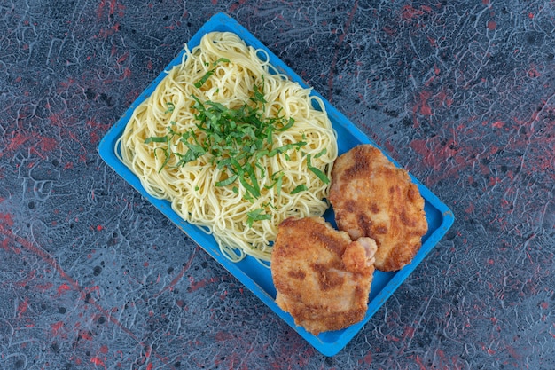 Foto gratuita una tabla de madera azul de fideos y chuletas de pollo.