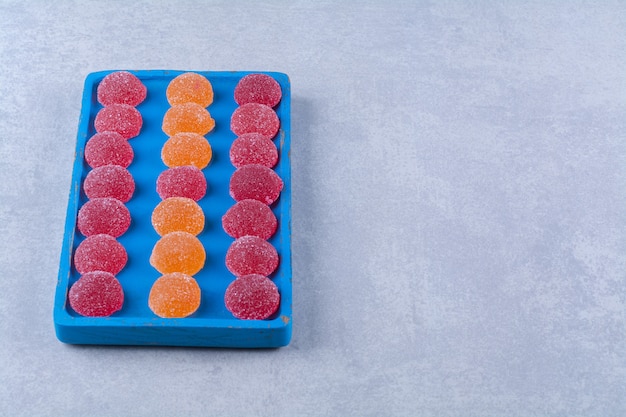 Una tabla de madera azul llena de mermeladas azucaradas rojas y naranjas