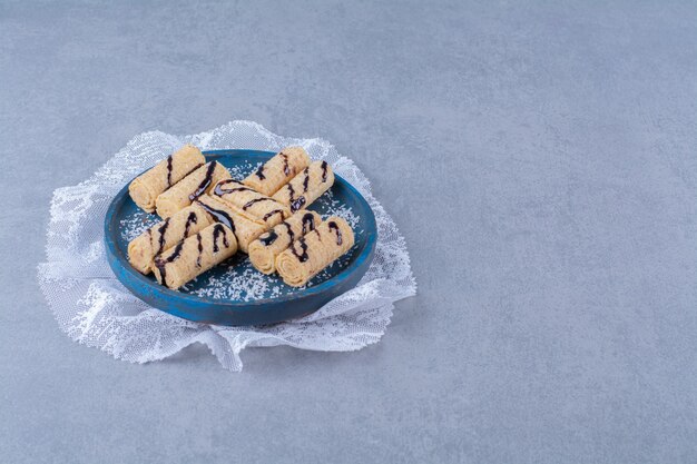 Una tabla de madera azul de palos dulces con chispas y jarabe de chocolate.