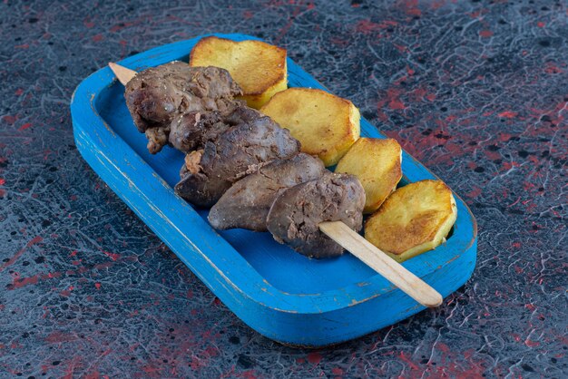 Foto gratuita una tabla de madera azul de patatas fritas con carne.