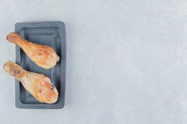 Una tabla de madera con carne de muslos de pollo frito.