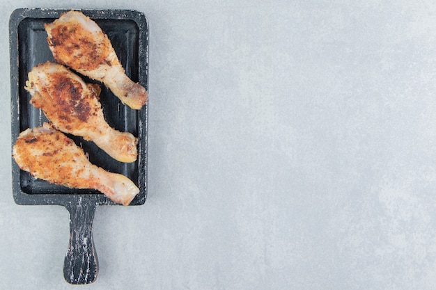 Una tabla de madera con carne de muslos de pollo frito.