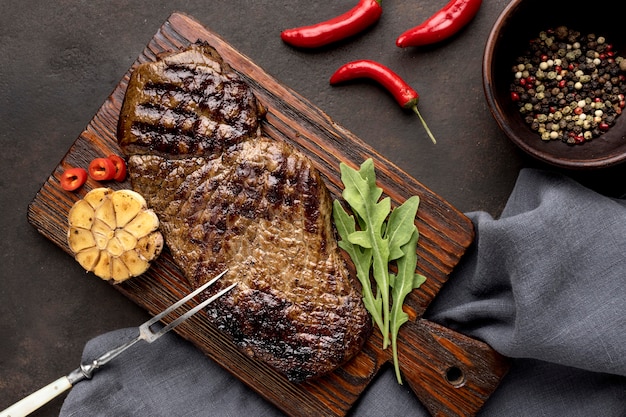 Tabla de madera con carne a la parrilla y condimento