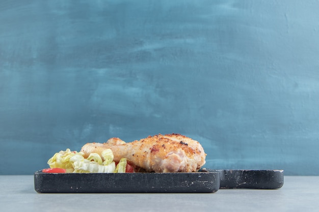 Una tabla de madera de carne de pollo frito con lechuga.