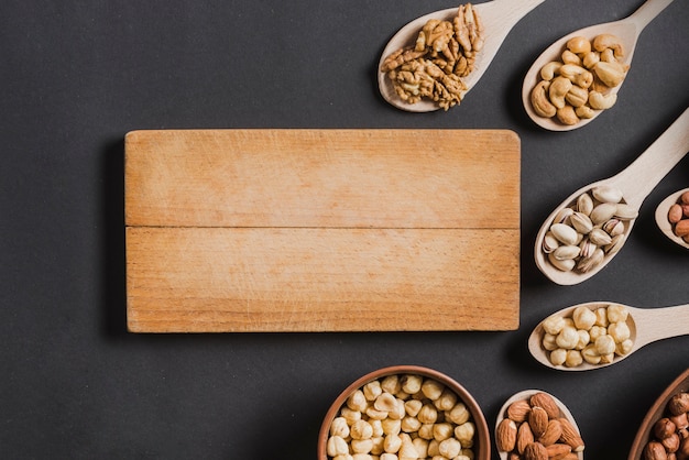 Tabla de madera cerca de cucharas y cuencos con nueces