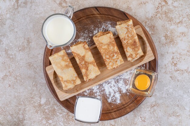 Una tabla de madera con deliciosas crepas y yema cruda.