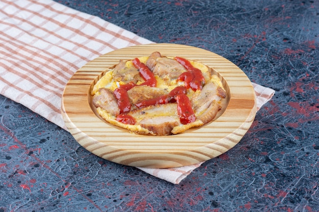 Una tabla de madera de delicioso huevo frito con carne y salsa de tomate.