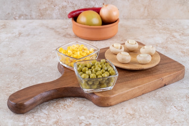 Una tabla de madera de diversas verduras sobre una superficie de mármol