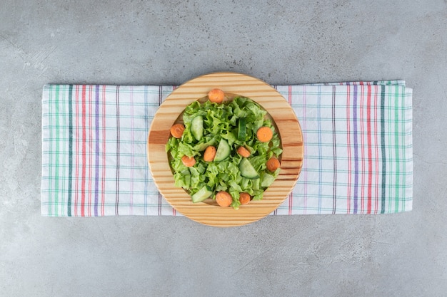 Foto gratuita una tabla de madera con ensalada de verduras sobre un mantel. foto de alta calidad