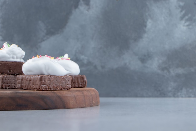 Una tabla de madera de galleta de chocolate con chispas de colores y crema. Foto de alta calidad