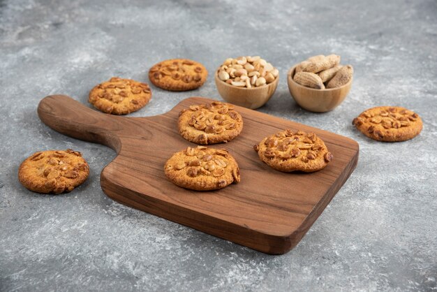 Foto gratuita tabla de madera de galletas caseras con maní orgánico sobre mesa de mármol.