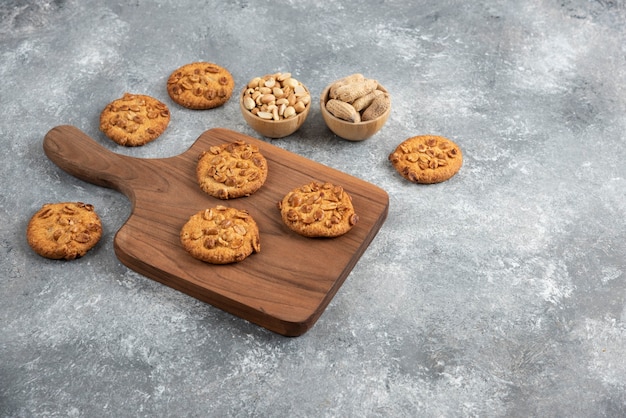 Tabla de madera de galletas caseras con maní orgánico sobre mesa de mármol.