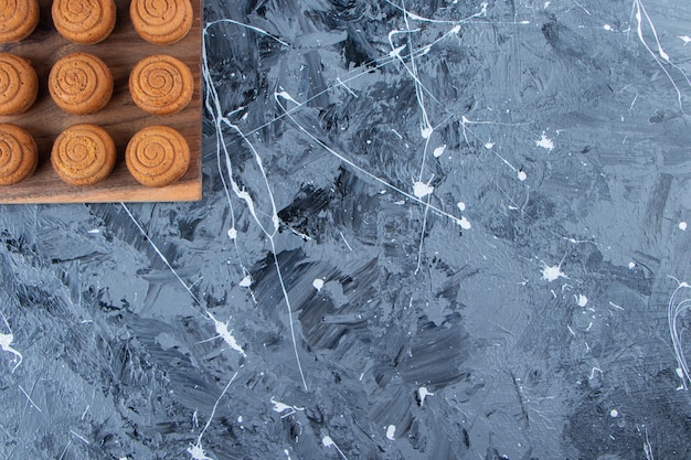 Foto gratuita una tabla de madera de galletas redondas dulces con una taza de cristal de sabroso café caliente sobre un fondo de mármol.