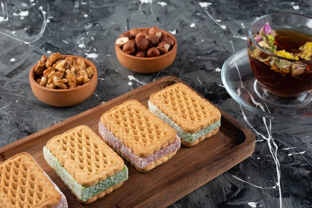 Una tabla de madera de gofres Belqian con una taza de té y nueces saludables