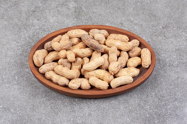 Una tabla de madera llena de cacahuetes con cáscara saludables