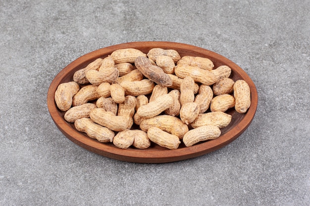 Una tabla de madera llena de cacahuetes con cáscara saludables