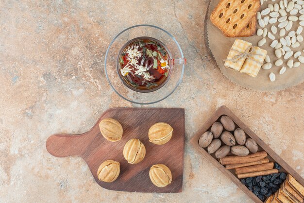 Una tabla de madera llena de galletas dulces y una taza de té de hierbas.