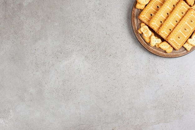 Una tabla de madera llena de galletas sobre fondo de mármol.