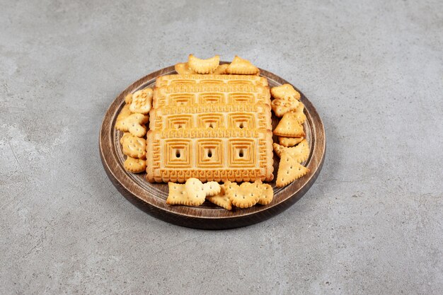 Una tabla de madera llena de galletas en la superficie de mármol