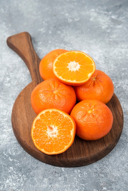 Una tabla de madera llena de jugosas frutas naranjas en la mesa de piedra.