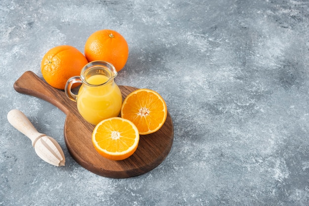 Una tabla de madera llena de jugosas rodajas de fruta naranja en la mesa de piedra.