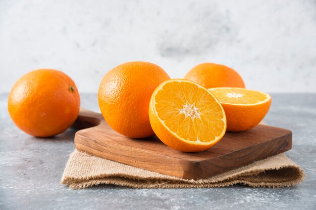 Una tabla de madera llena de jugosas rodajas de fruta naranja en la mesa de piedra.