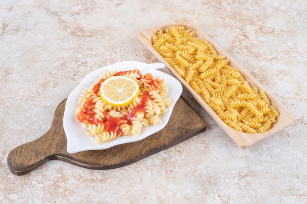 Foto gratuita una tabla de madera de macarrones crudos en espiral y verduras