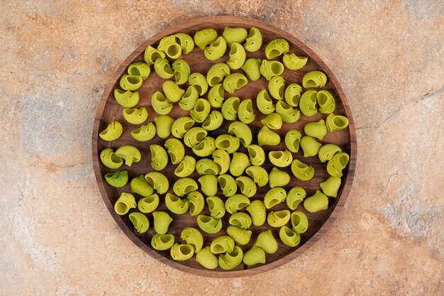 Una tabla de madera con macarrones verdes sin preparar.