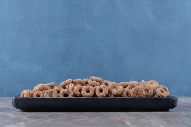 Una tabla de madera negra de anillos de cereales de chocolate saludables para el desayuno.