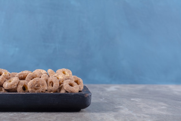 Una tabla de madera negra de anillos de cereales de chocolate saludables para el desayuno.