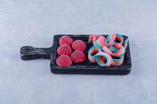 Una tabla de madera negra llena de dulces coloridos azucarados.