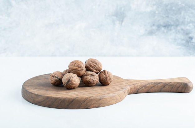 Una tabla de madera con nueces saludables sobre un fondo blanco.