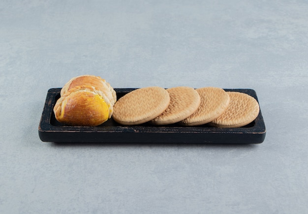 Una tabla de madera oscura con dulces galletas redondas.