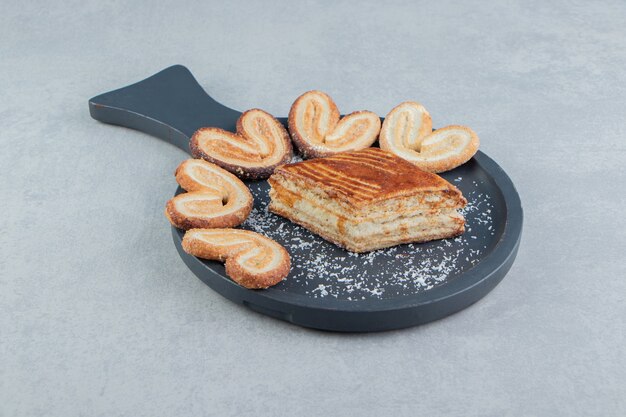 Una tabla de madera oscura con galletas dulces en forma de corazón.